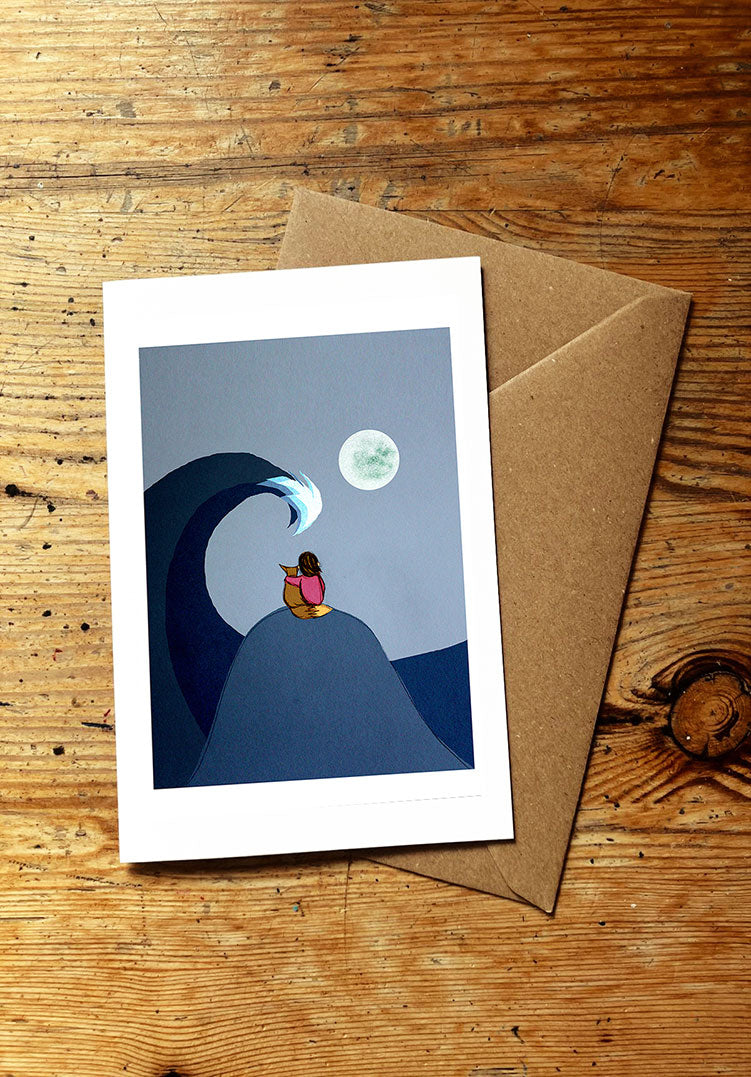 Greeting card with a wave and moon design and a fox and a girl on a wooden surface
