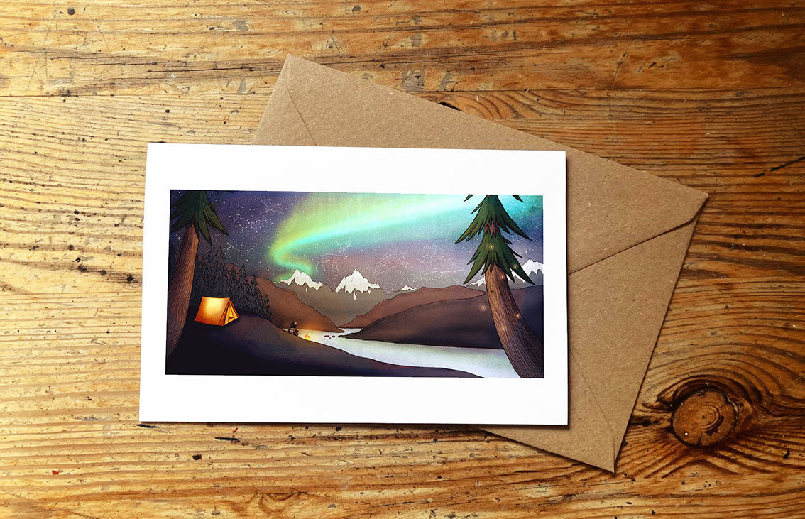 Greeting card with Northern Lights wild camping design on a wooden surface