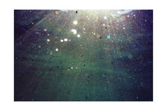 particles of sand floating and catching the sun and shimmering under the sea