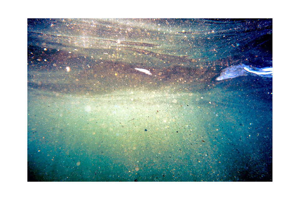 sand particles catching the sun light as they float and shimmer underwater