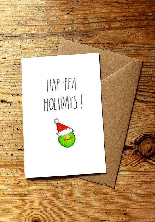 Christmas card with 'Hap-Pea Holidays!' text and a pea wearing a Santa hat on a wooden surface.
