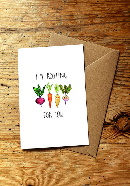 Veg pun greeting card with smiley vegetables illustration and 'I'm rooting for you' text on a wooden surface