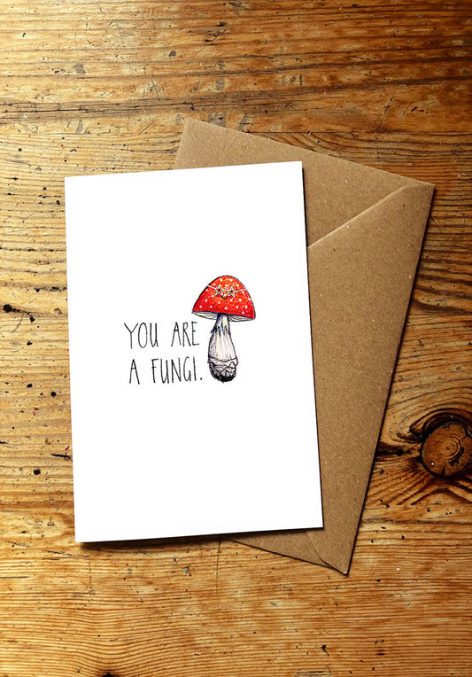 Veg pun greeting card with smiley mushroom illustration and text 'You are a fungi' on a wooden surface