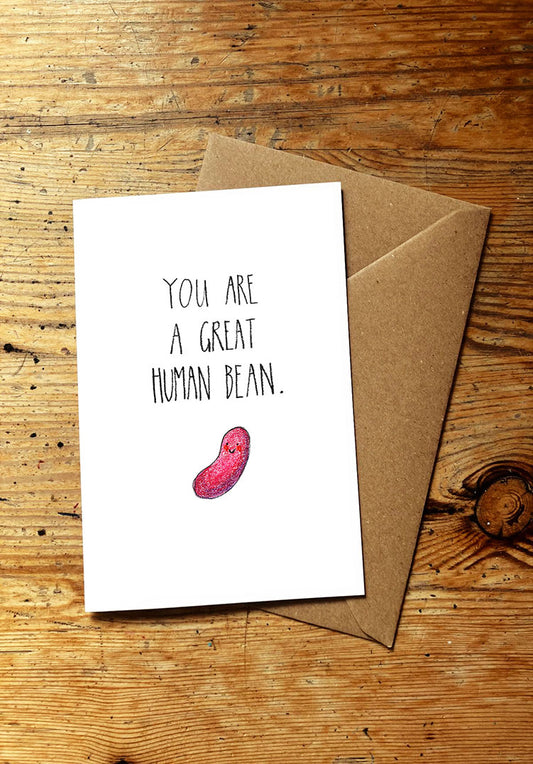 Veg oun greeting card with 'You are a great human bean' text and a smiley bean illustration on a wooden surface.