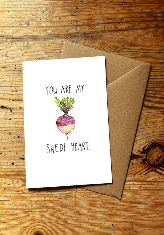 Veg pun greeting card with smiley swede illustration and text on a wooden surface