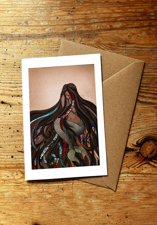 Greeting card with an illustration of a crying mermaid with ocean plastic tangled in her hair on a wooden surface