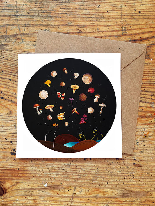Greeting card with space-themed design featuring wild edible mushrooms on a wooden surface