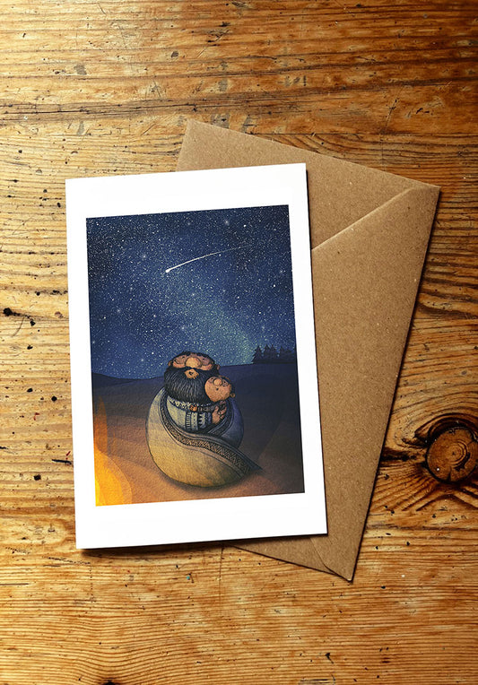 Greeting card with illustration of a father and son watching a starry night sky whilst sitting by a camp fire, on a wooden surface