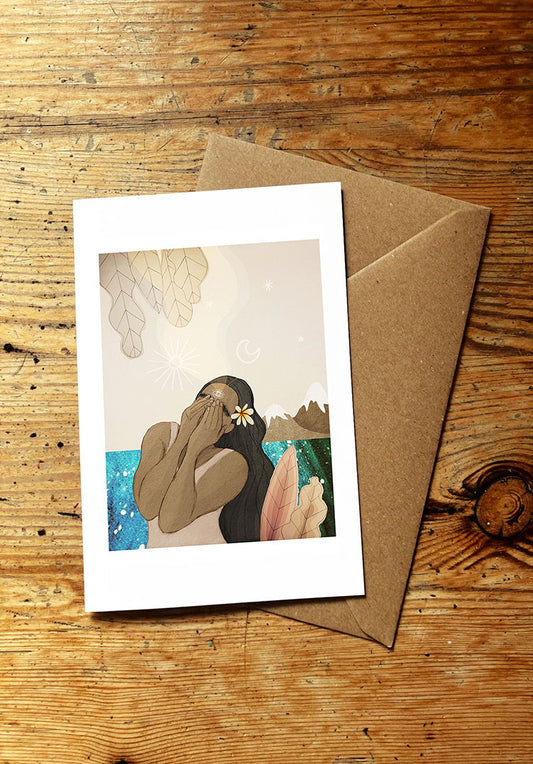 Greeting card with an illustration of a woman and ocean and mountains on a wooden surface