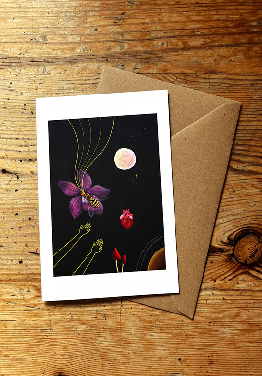 Greeting card with a cosmic illustration with a flower, bee, heart, full moon, planet and mushrooms, on a wooden surface
