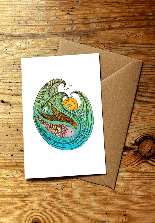 Greeting card with fish, bird, sunset and ocean wave design on a wooden surface