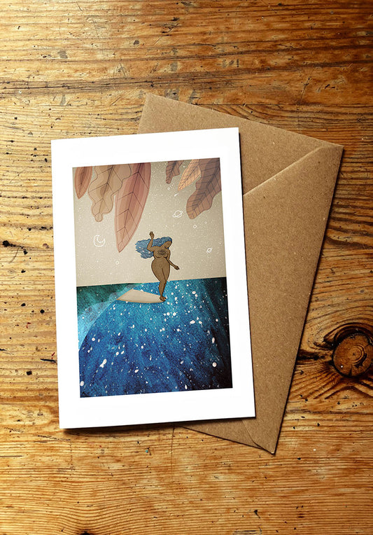 Greeting card with a surf girl surfing an ocean wave, with brown envelope  on a wooden surface