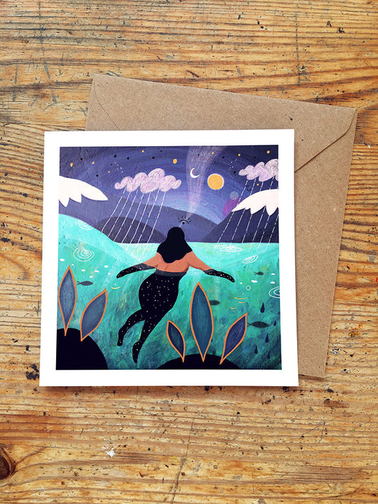Greeting card with wild swimming scene and envelope on wooden surface