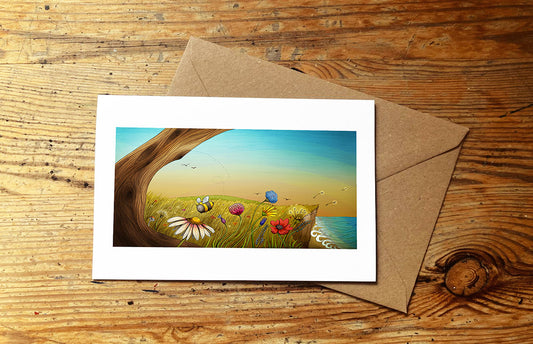 Greeting card with wild flower and beach scene and envelope on wooden surface
